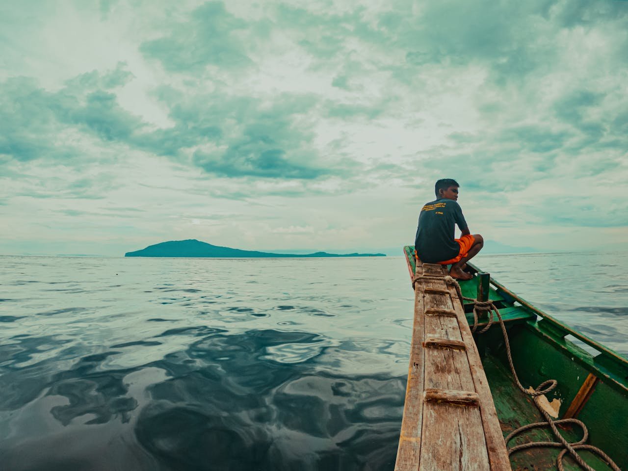 A teenager on a wooden boat in the ocean near Batangas, Philippines.